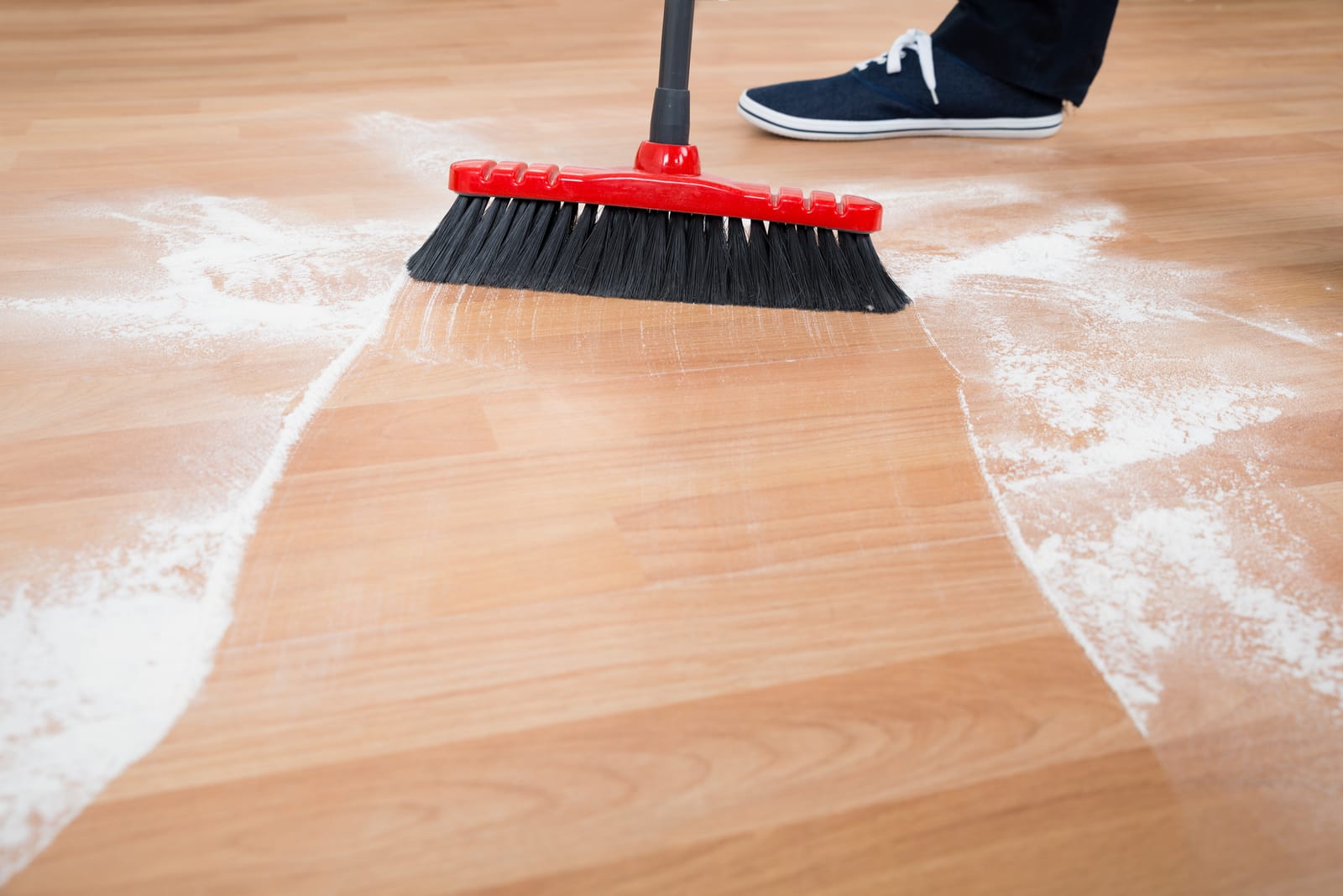 man sweeping hardwood floor