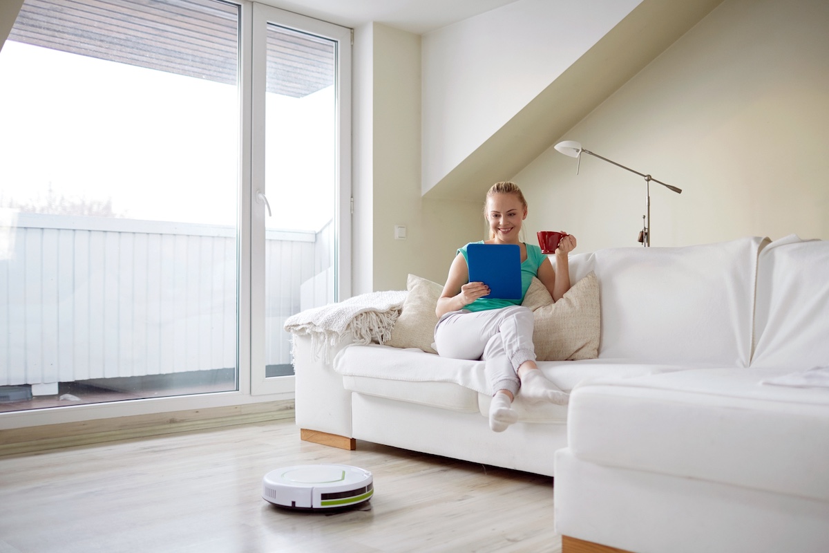 Silent robot vacuum cleaner at work while woman reads a book