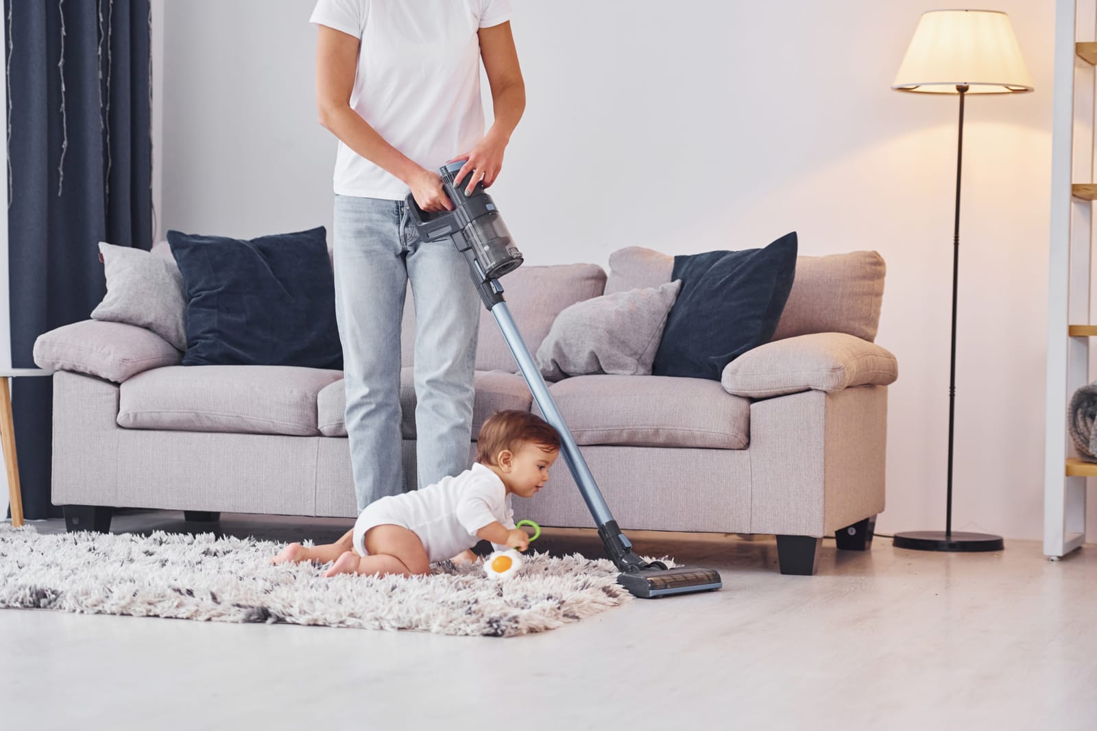 using of the vacuum cleaner mother with her little daughter is indoors at home together