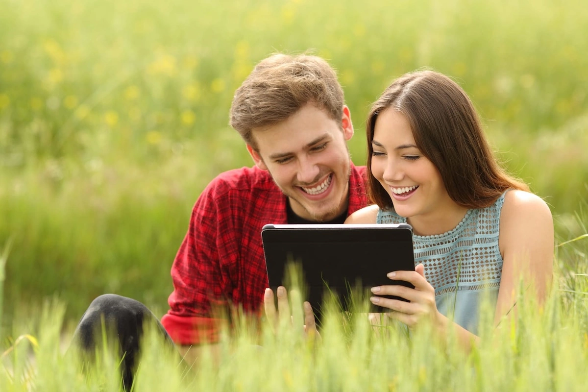 couple watching videos in a tablet in a field