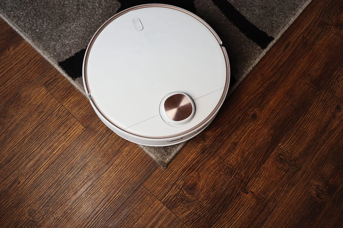 Robotic vacuum cleaner on laminate wood floor and the carpet in living room