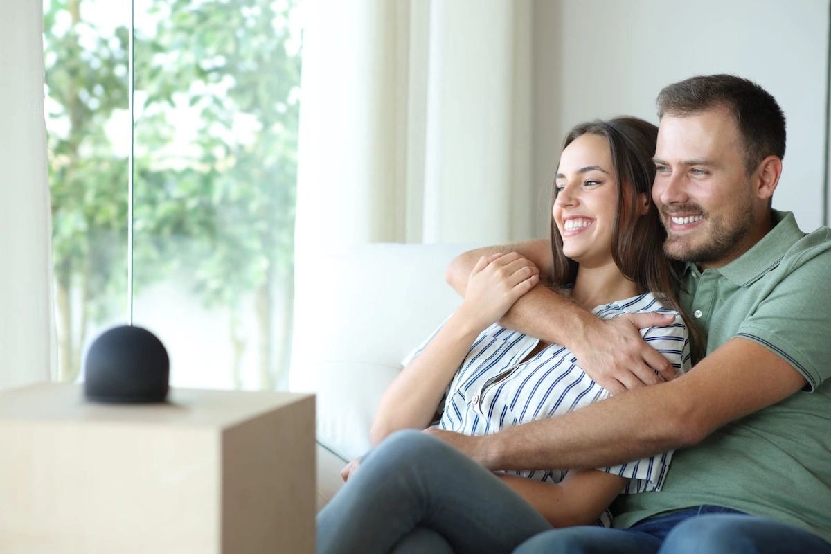 happy couple with smart speaker enjoying at home